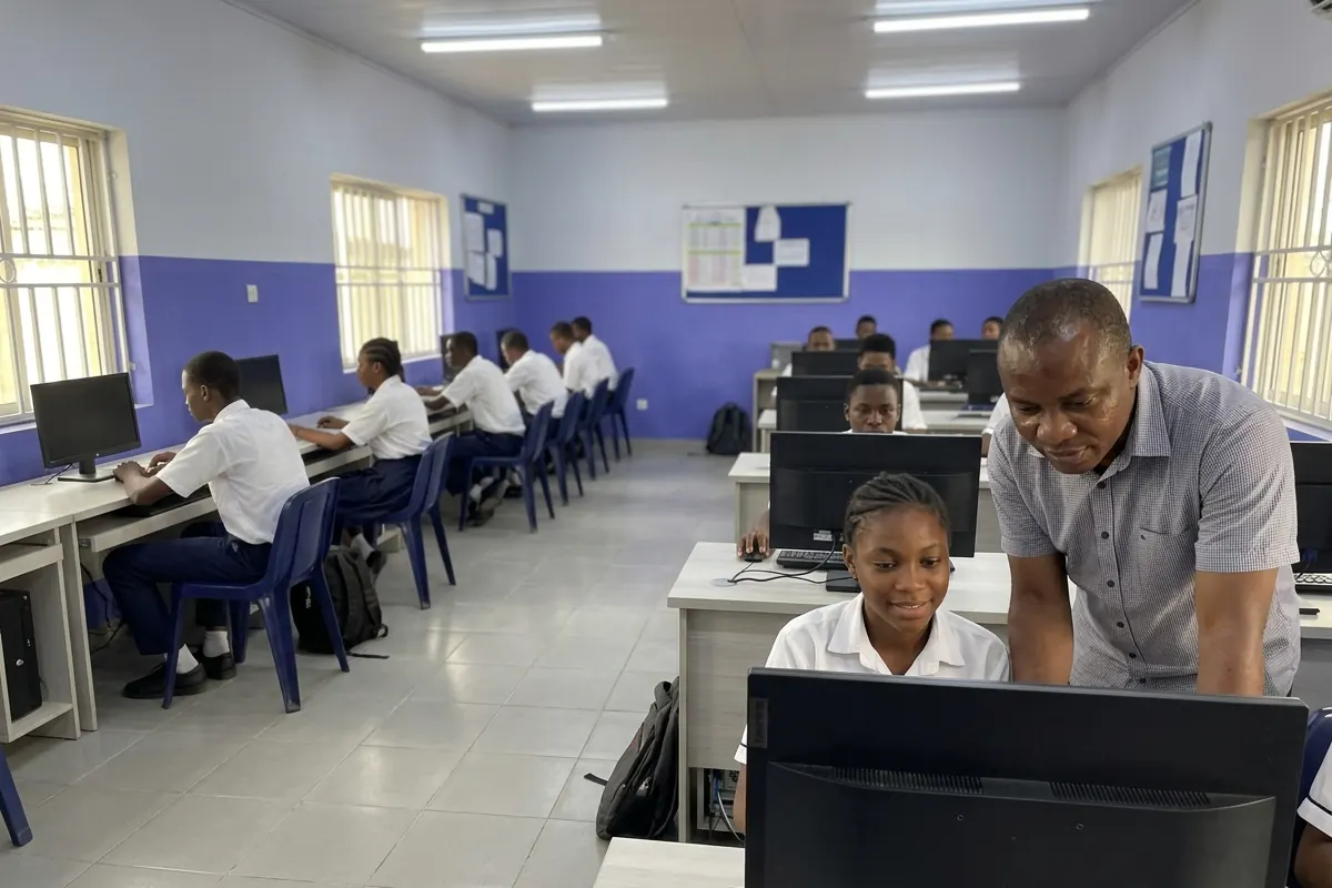 A teacher helping a student in a school computer lab